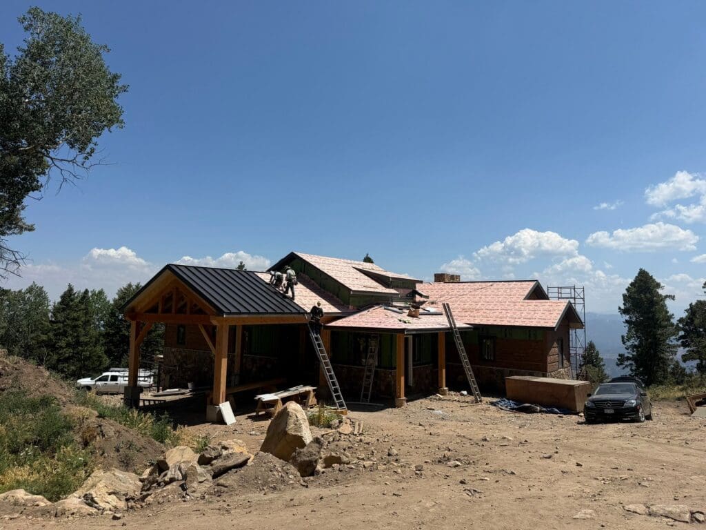 in progress look at the installation of a black metal standing seam roof being installed on a residential home in the foothills of Evergreen CO